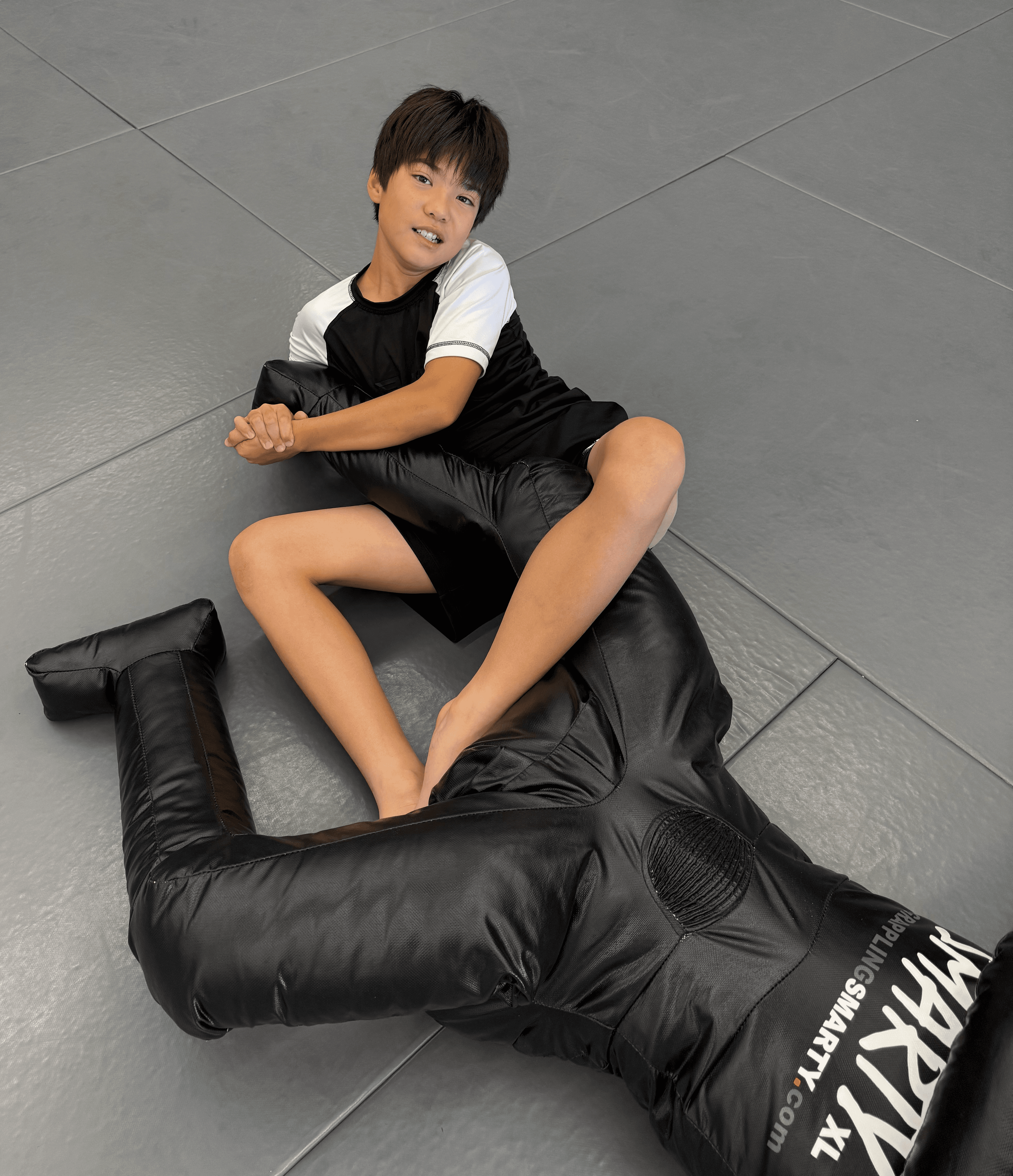 Kids BJJ student practicing a heel hook on a grappling dummy