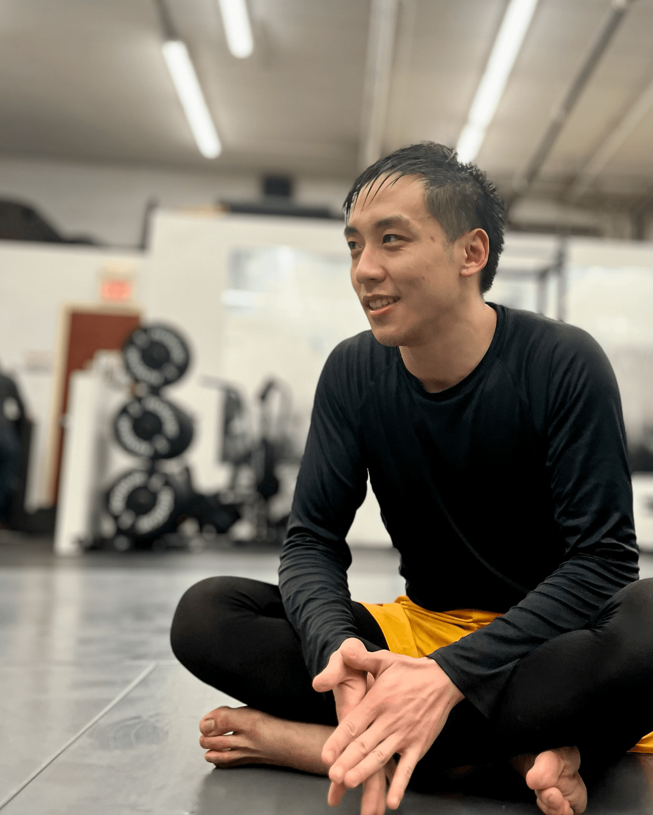 Assistant instructor Alex Tsang sitting on the mats.